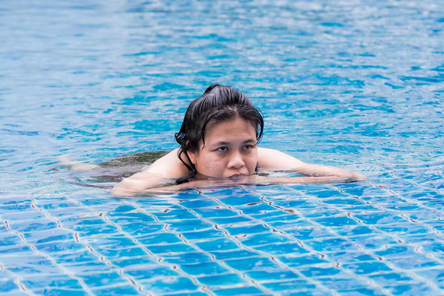 Woman is taking a dip in the swimming pool. A moment of relaxation. photo