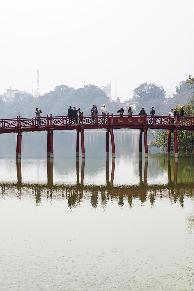 hanoi, vietnam, 2 de marzo de 2017 - personas no identificadas en huc bridge en hanoi, vietnam. este puente rojo de madera conecta la isla de jade con la orilla del lago hoan kiem. foto