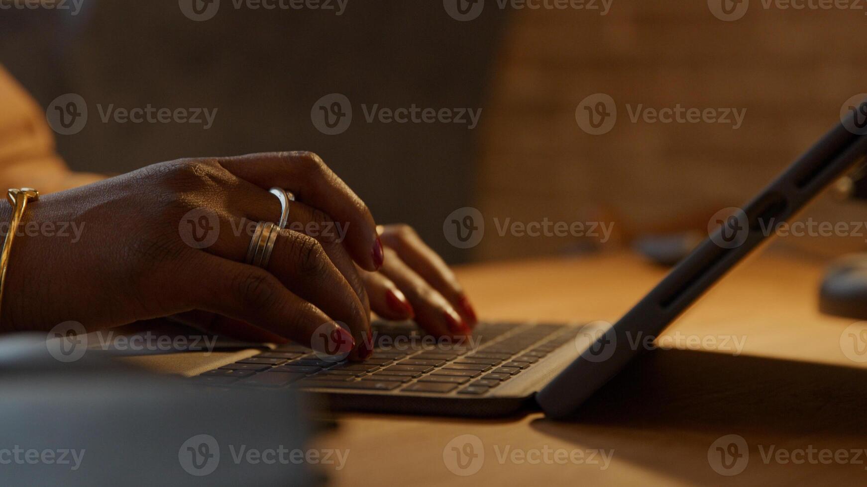 Cerca de los dedos de la mujer negra madura escribiendo en el portátil foto