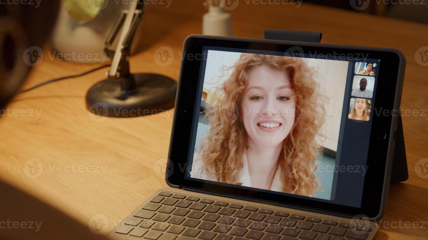 Mature black woman sits at table, having video call with young white woman who talks photo