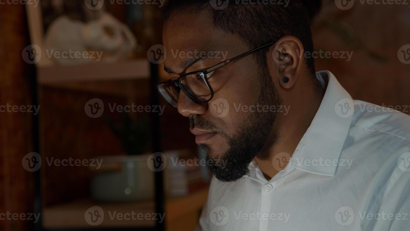 Close up of typing fingers on laptop of black man wearing glasses, screen reflection on face photo