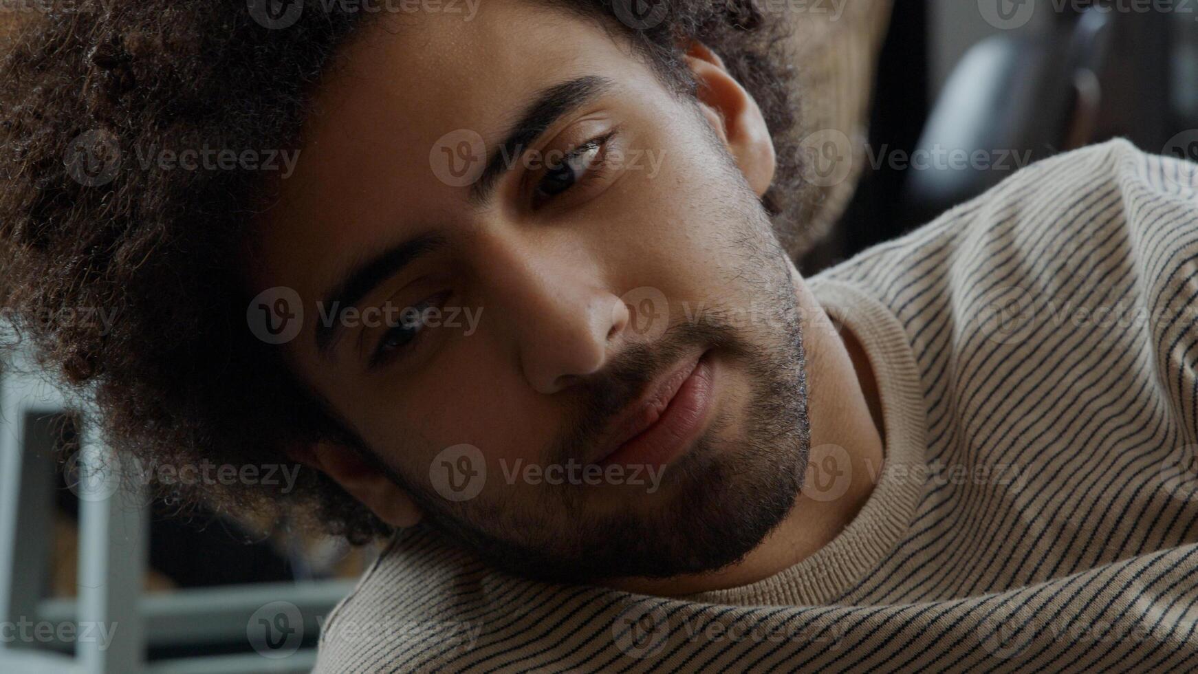 Close up of young Middle Eastern man, lying on his side on the floor, looking, talking photo