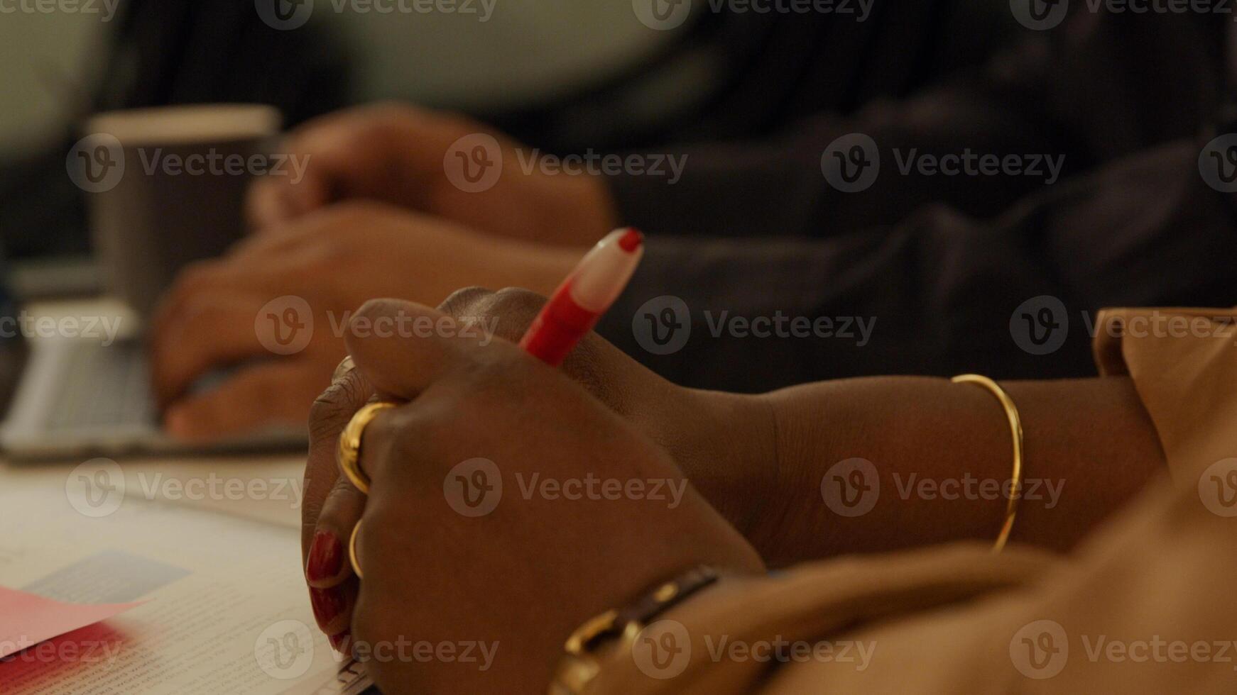 Cerca de las manos sobre la mesa de la mujer madura negra, sosteniendo la pluma foto