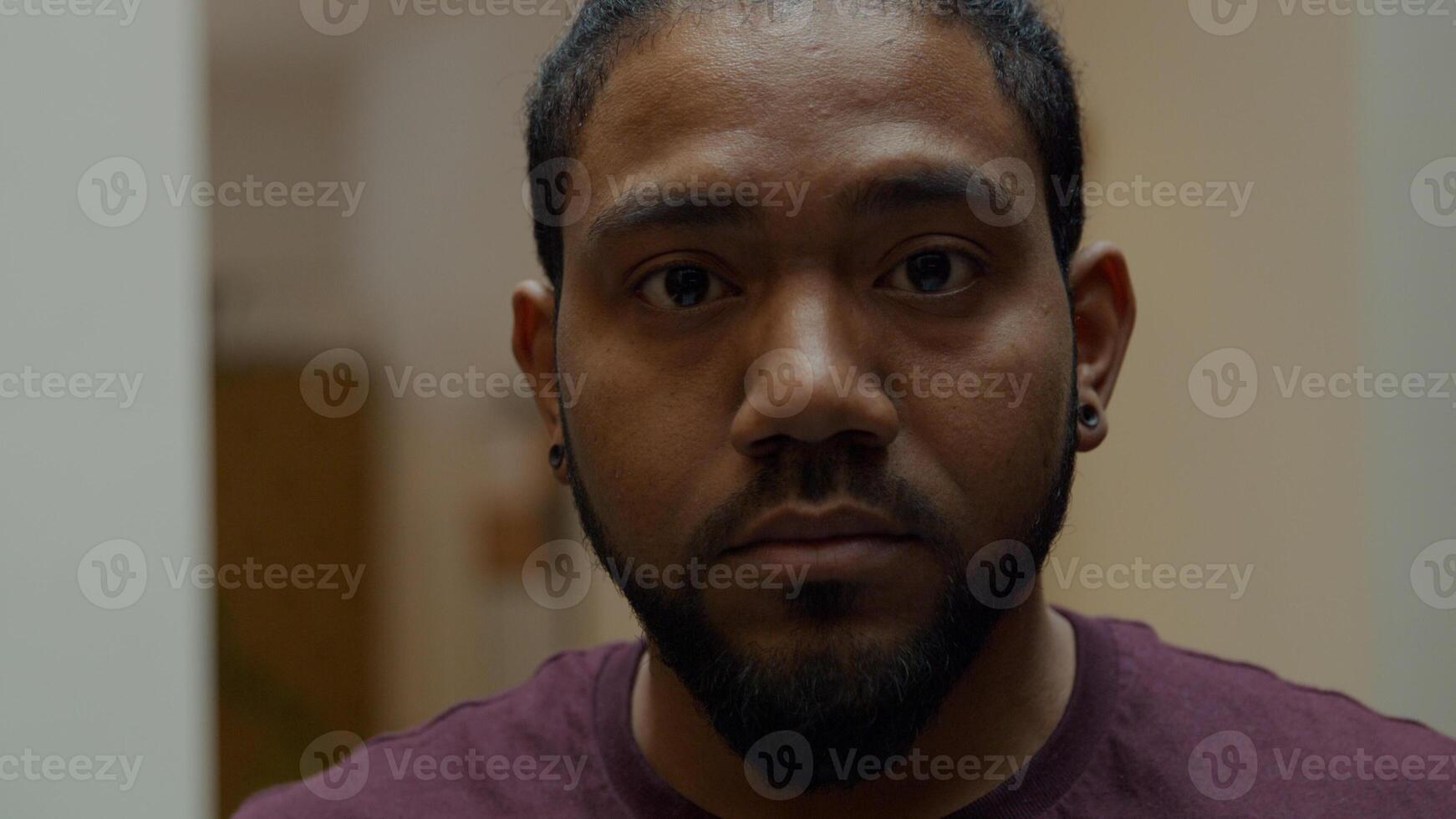 Close up of black man, looking down, lifts head, looking in camera lens photo