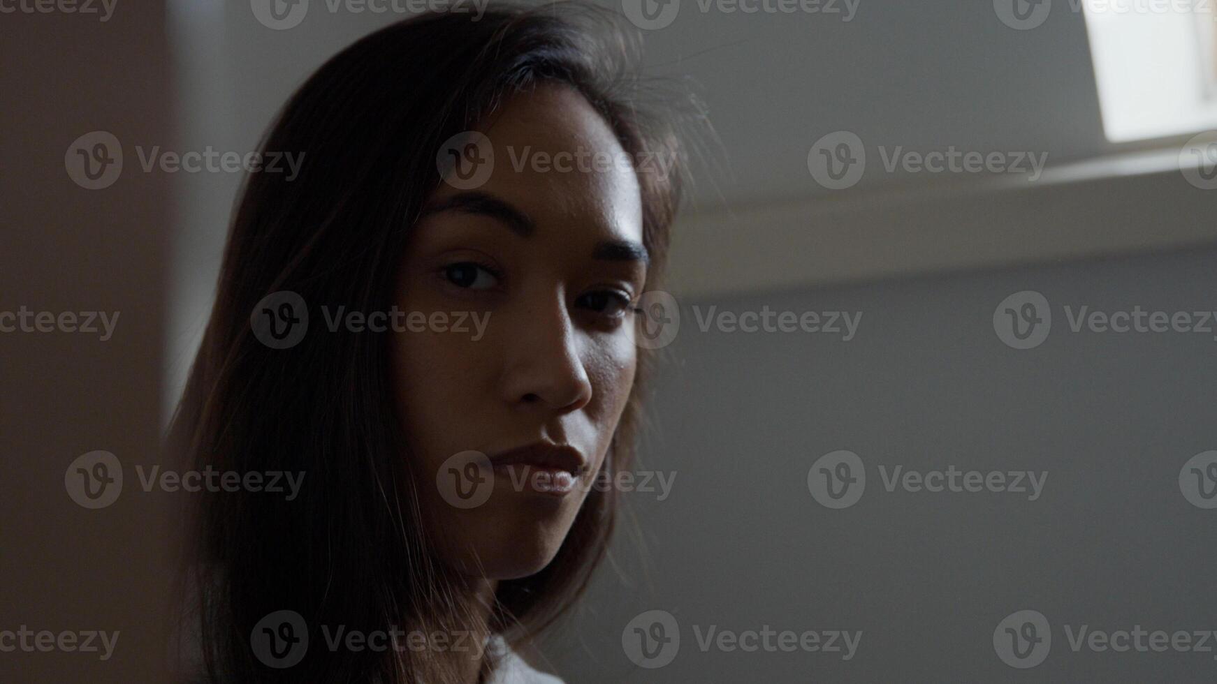 Close up, profile of young mixed race woman, looking straight ahead, turns face to camera, eyes blinking photo