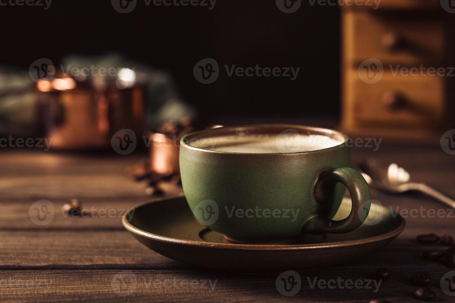 Green cup of coffee with coffee grinder photo
