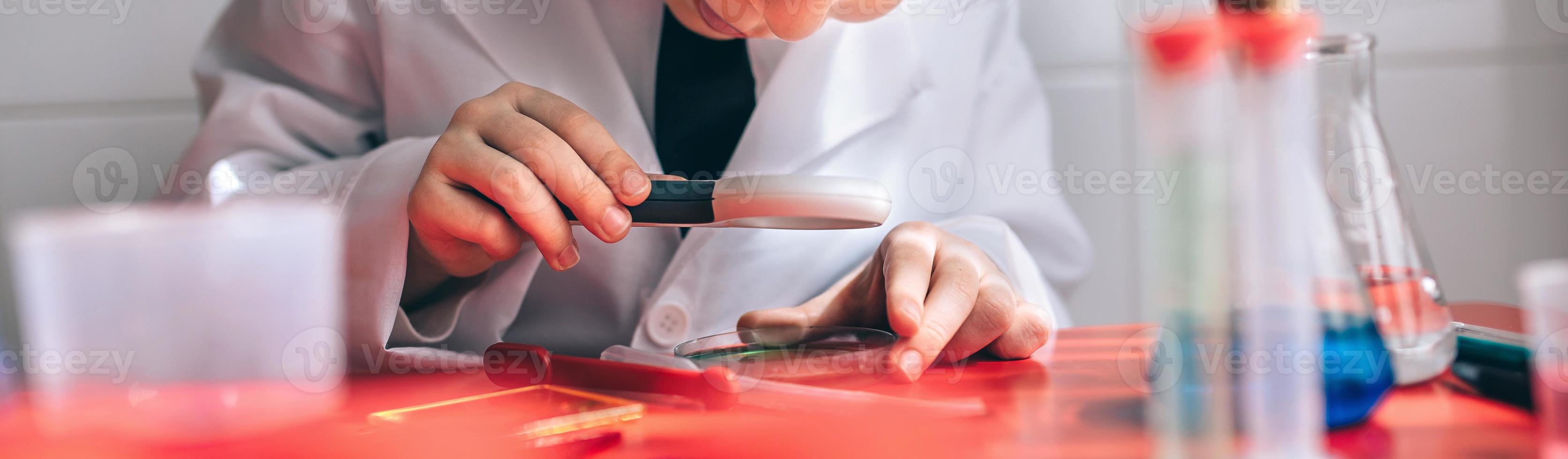 Happy kid looking liquid through magnifying glass photo