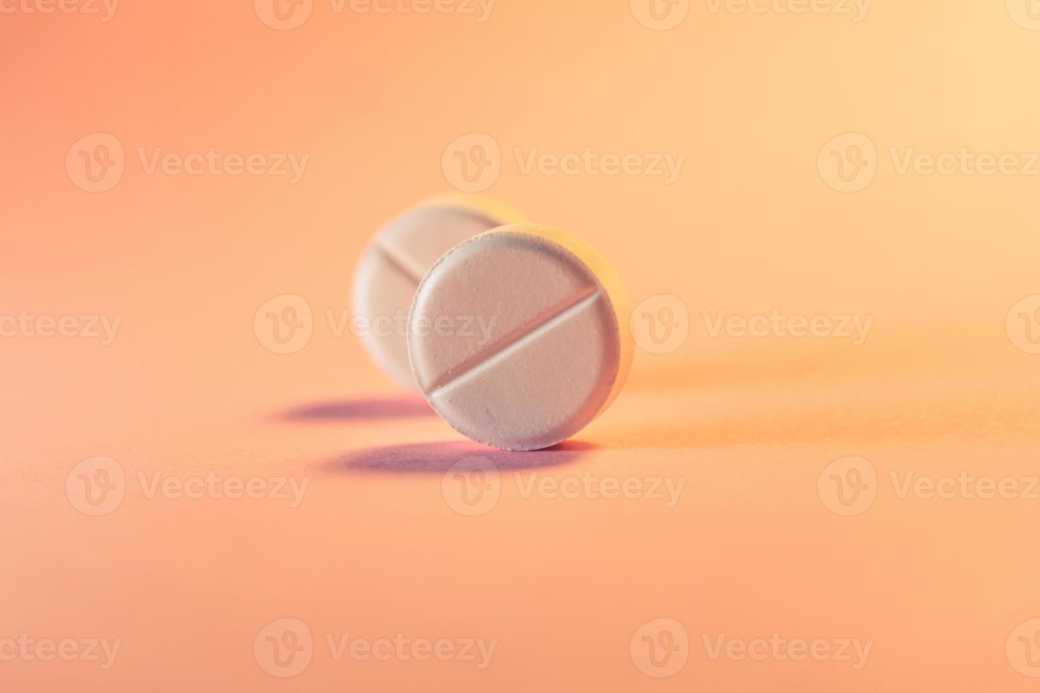 Two pills in an orange-pink background. Medical theme. photo