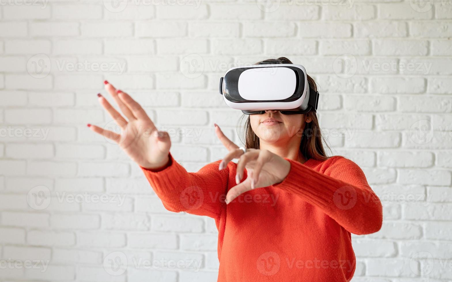 Smile happy woman getting experience using VR-headset glasses of virtual reality at home much gesticulating hands photo