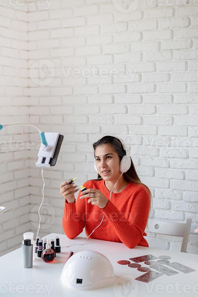 Hermosa influenciadora maestra de uñas caucásica con video chat o haciendo un blog foto