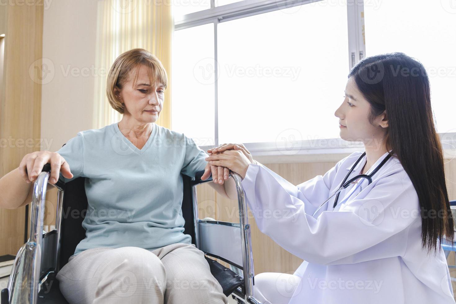 female doctor gives advice and encourages the old woman patient in a wheelchair photo