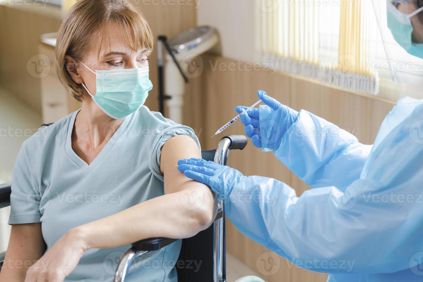 Paciente anciana recibiendo la vacuna covid-19 o coronavirus en silla de ruedas foto