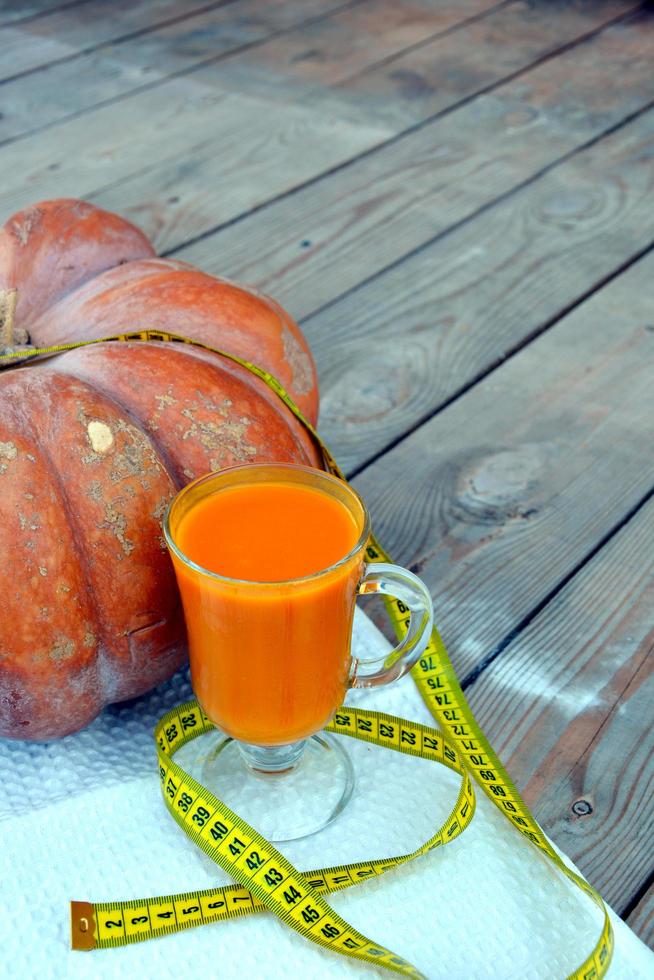 calabaza y jugo de calabaza en una copa de vidrio. verduras sobre un fondo de madera. foto