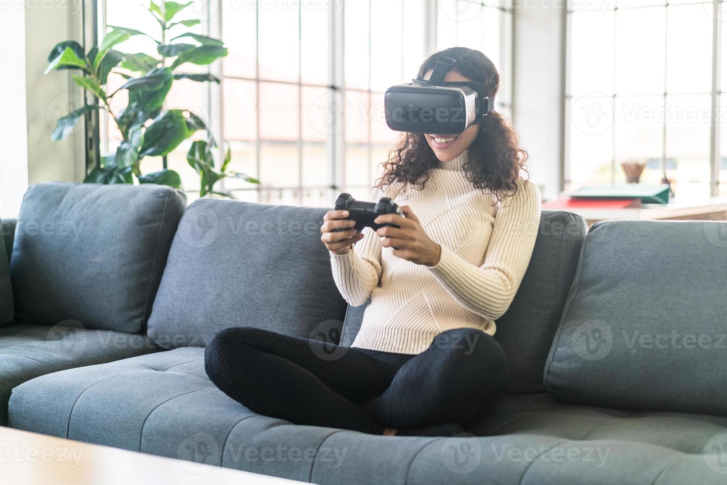 Mujer latina con un casco de realidad virtual en el sofá foto