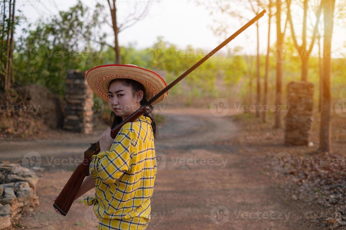 retrato, el, agricultor, asea, mujer, llevando, un, sombrero, mano, tenencia, avancarga, pistola, vendimia, en, el, granja, niña joven, con, rifle de aire comprimido, un, jardín foto