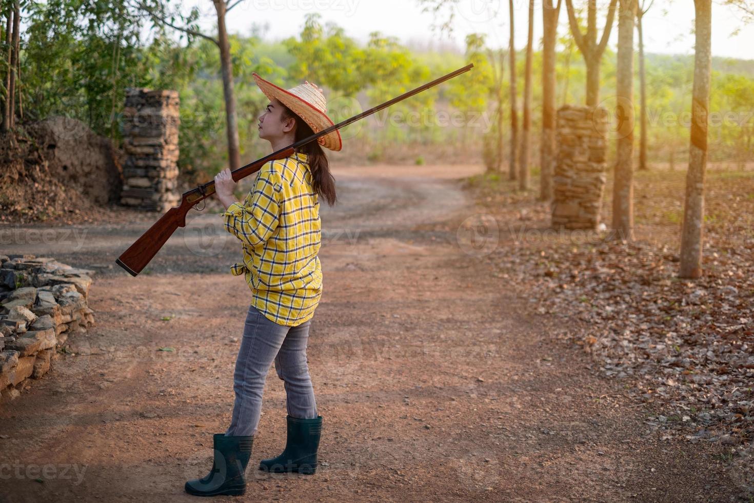 Portrait the farmer asea woman wearing a hat hand holding muzzle-loading vintage gun in the farm, Young girl with air rifle a garden photo