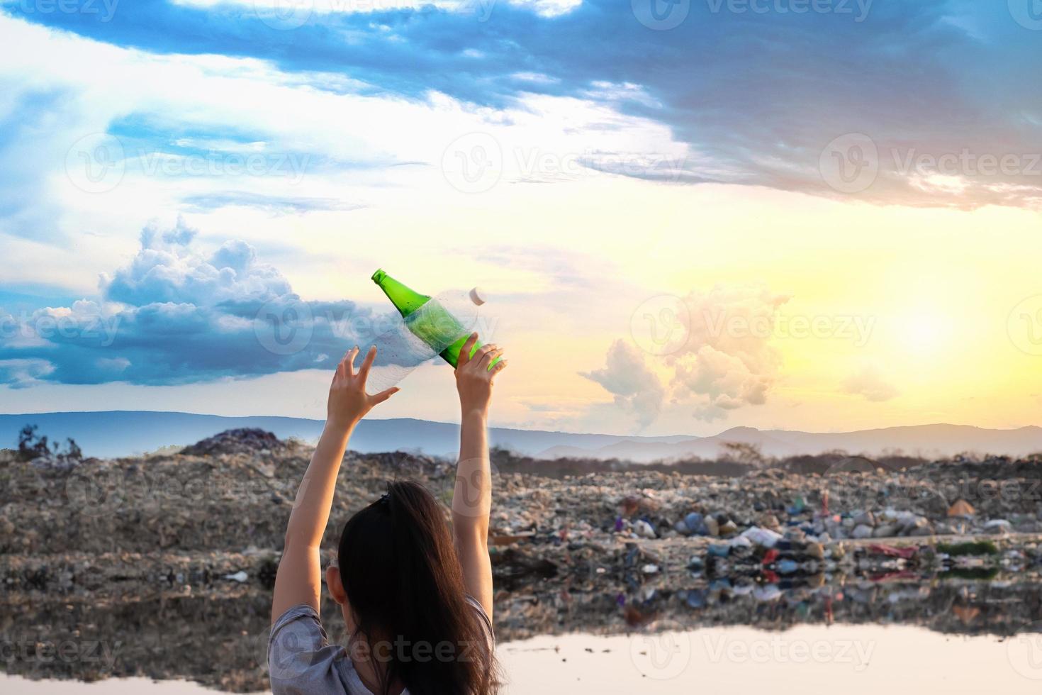 The back woman stands in hand have green glass bottle and clear plastic bottle at mountain large garbage background photo