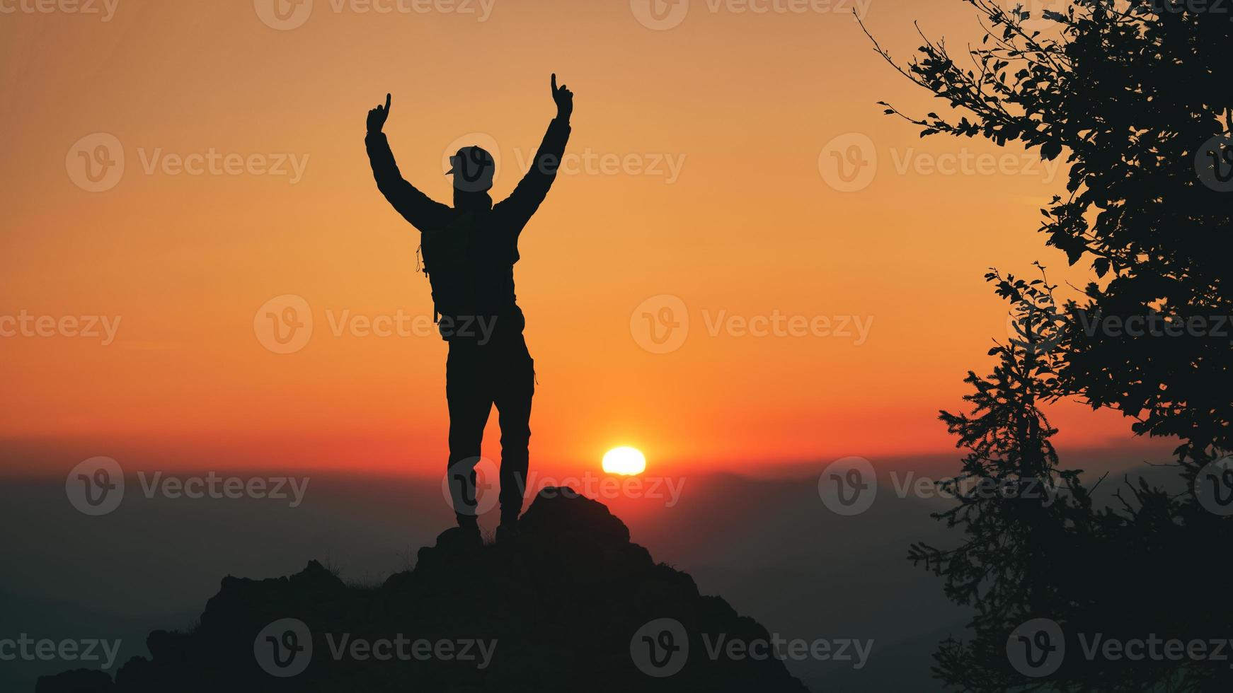 Hombre en silueta frente a la idílica puesta de sol en las colinas foto