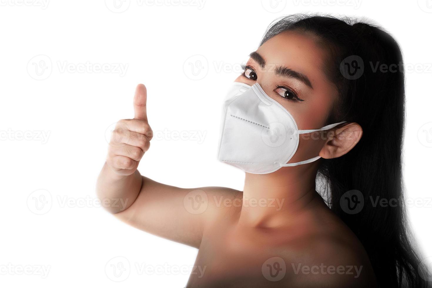 Close up of a woman putting on a respirator N95 mask to protect from airborne respiratory diseases as the flu covid-19 corona PM2.5 dust and smog, Female thumbs-up gesture with hand photo