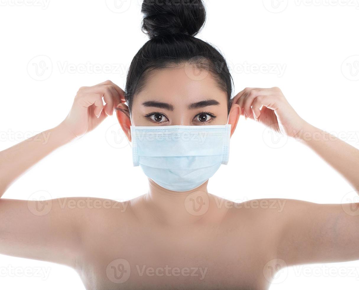 Beautiful young Asia woman putting on a medical mask to protect from airborne respiratory diseases as the flu covid-19 PM2.5 dust and smog, Women safety virus infection concept, look camera photo