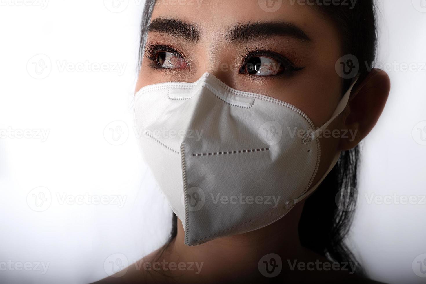 Cerca de una joven mujer asiática poniéndose una mascarilla médica para protegerse de enfermedades respiratorias transmitidas por el aire como la gripe covid-19 pm2.5 polvo y smog en fondo gris, concepto de infección por virus de seguridad foto