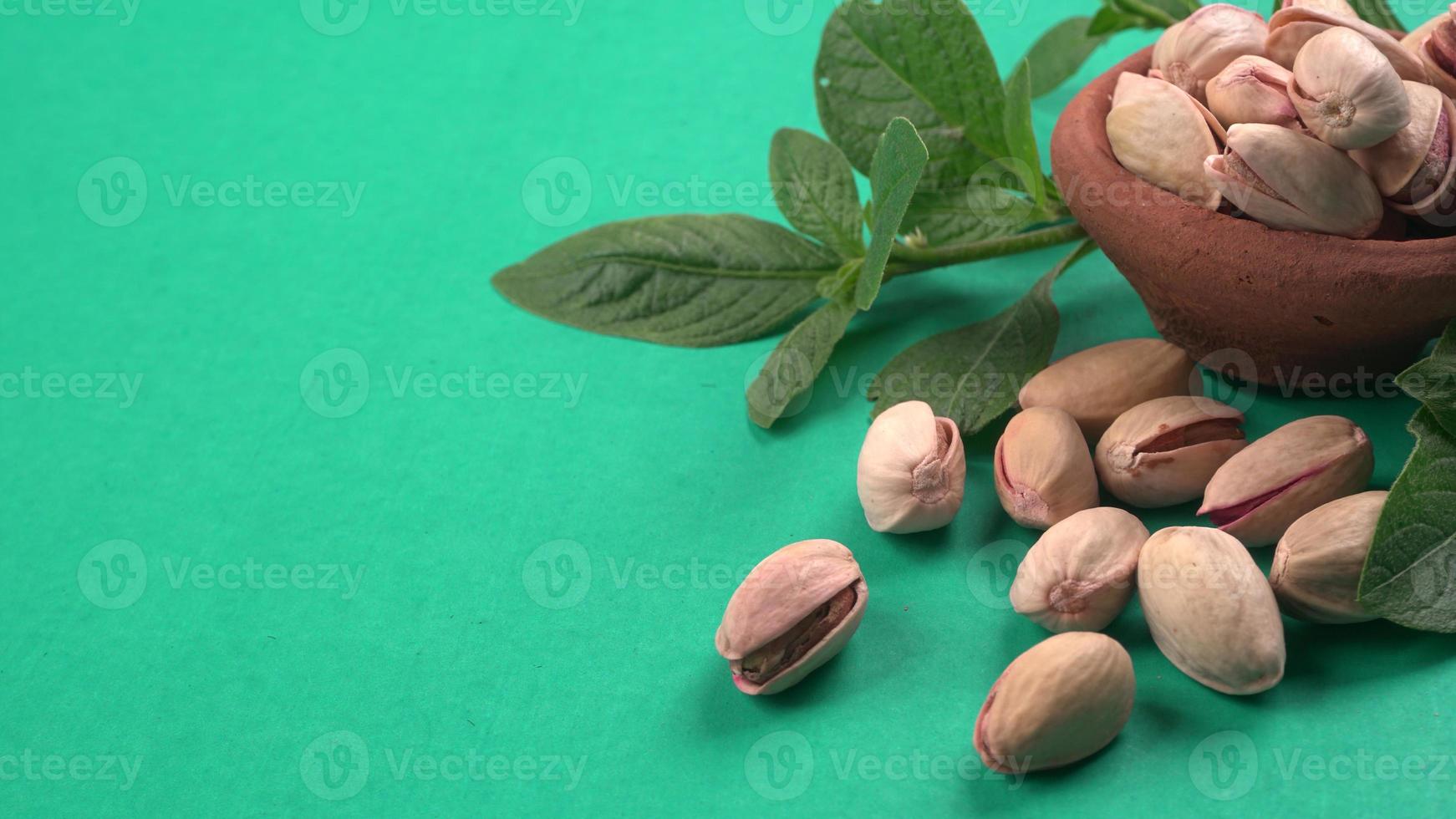 Pistachios or Pista nuts decorated with green leaves. plain background, top view.Flat lay. photo