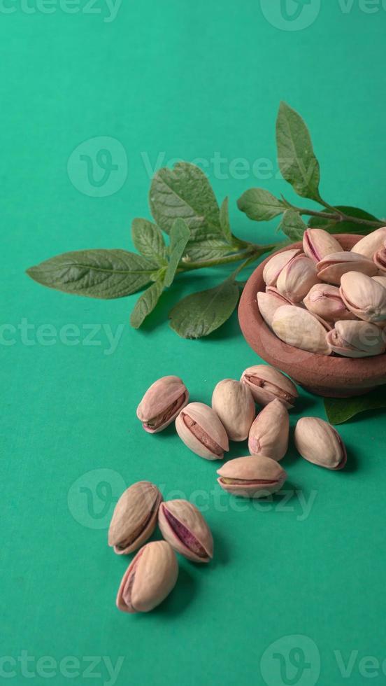 Pistachios or Pista nuts decorated with green leaves. plain background, top view.Flat lay. photo