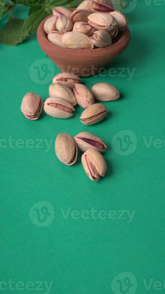 Pistachios or Pista nuts decorated with green leaves. plain background, top view.Flat lay. photo