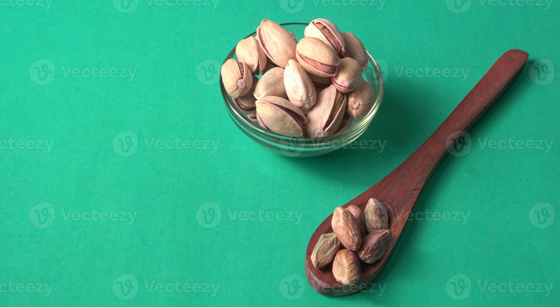 Pistachios or Pista nuts decorated with green leaves. plain background, top view.Flat lay. photo