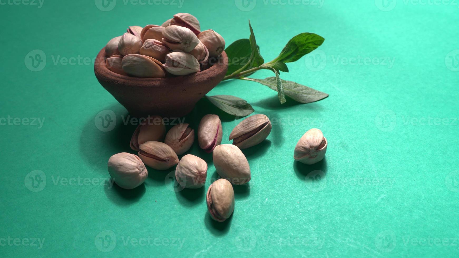 Pistachios or Pista nuts decorated with green leaves. plain background, top view.Flat lay. photo