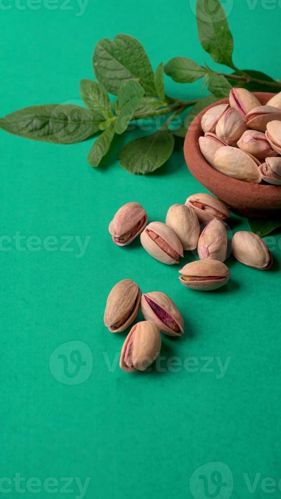 Pistachios or Pista nuts decorated with green leaves. plain background, top view.Flat lay. photo
