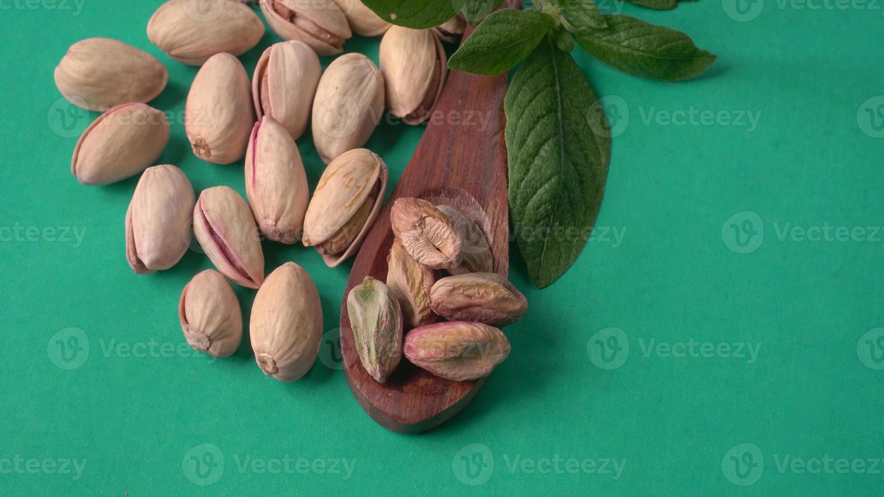 Pistachios or Pista nuts decorated with green leaves. plain background, top view.Flat lay. photo