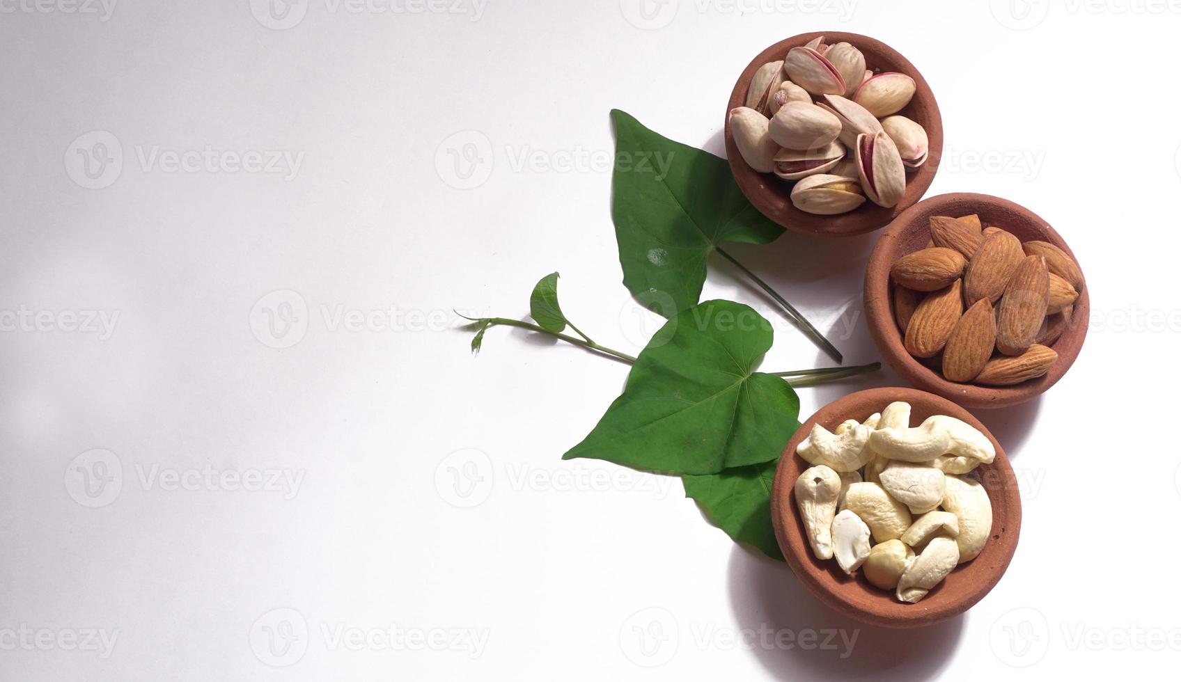 Pistachios or Pista nuts decorated with green leaves. plain background, top view.Flat lay. photo