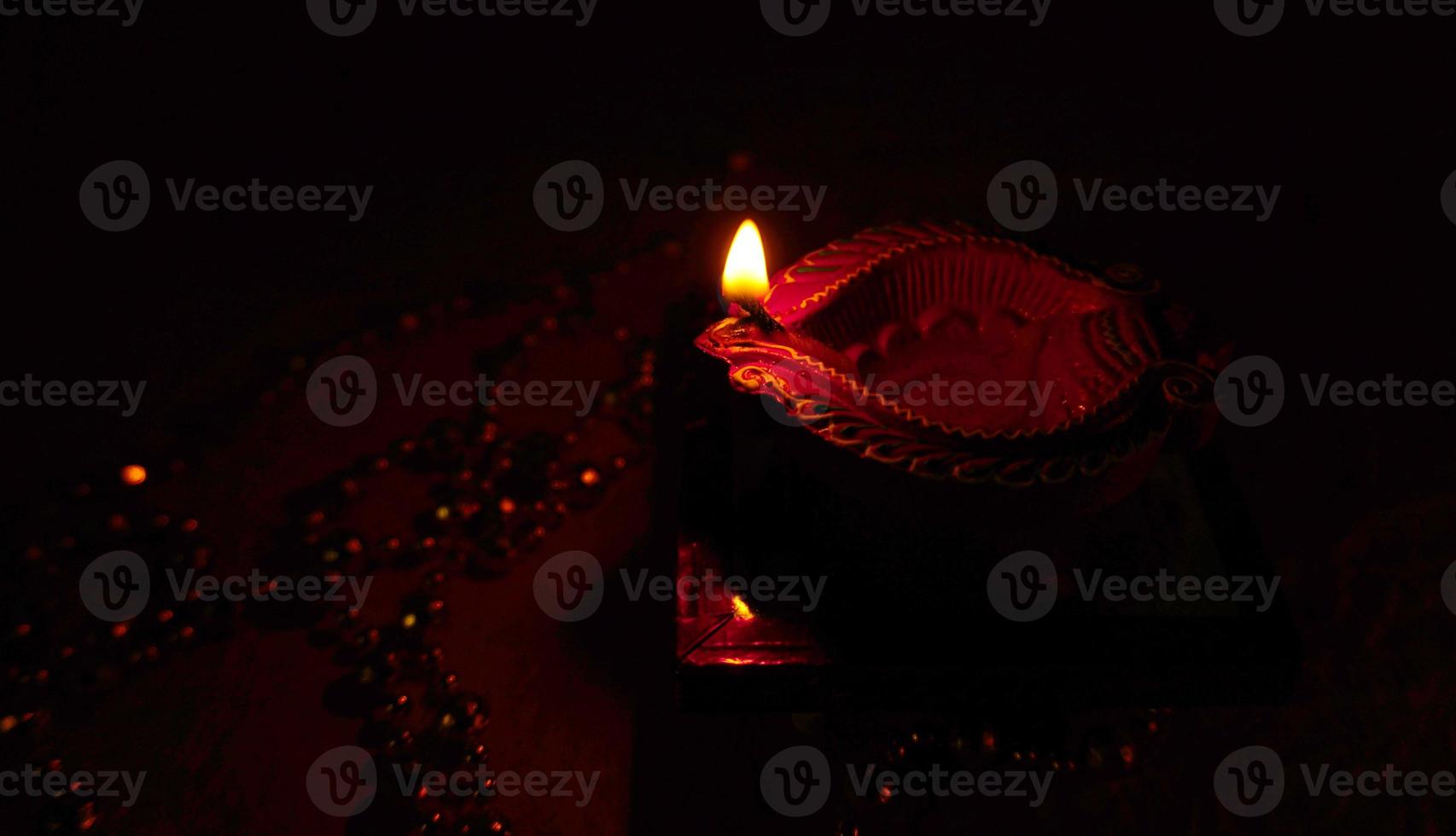 Happy Diwali - Diya lamps lit during Diwali celebration. Colourful and decorated lantern are lit in night on this occassion with flower rangoli, sweets and gifts. photo
