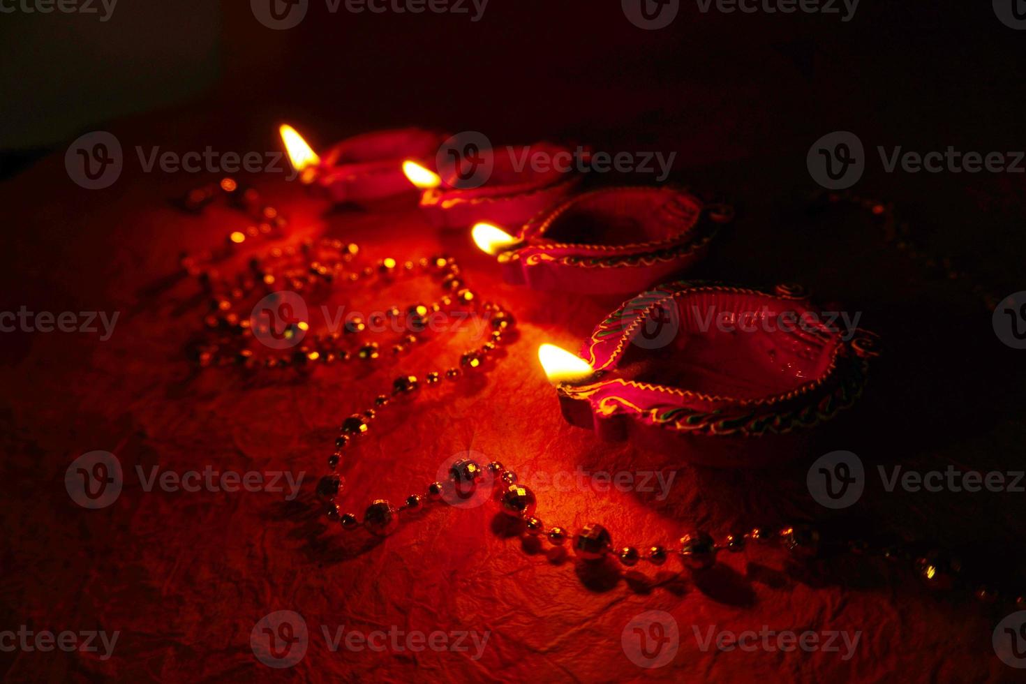 Happy Diwali - Diya lamps lit during Diwali celebration. Colourful and decorated lantern are lit in night on this occassion with flower rangoli, sweets and gifts. photo