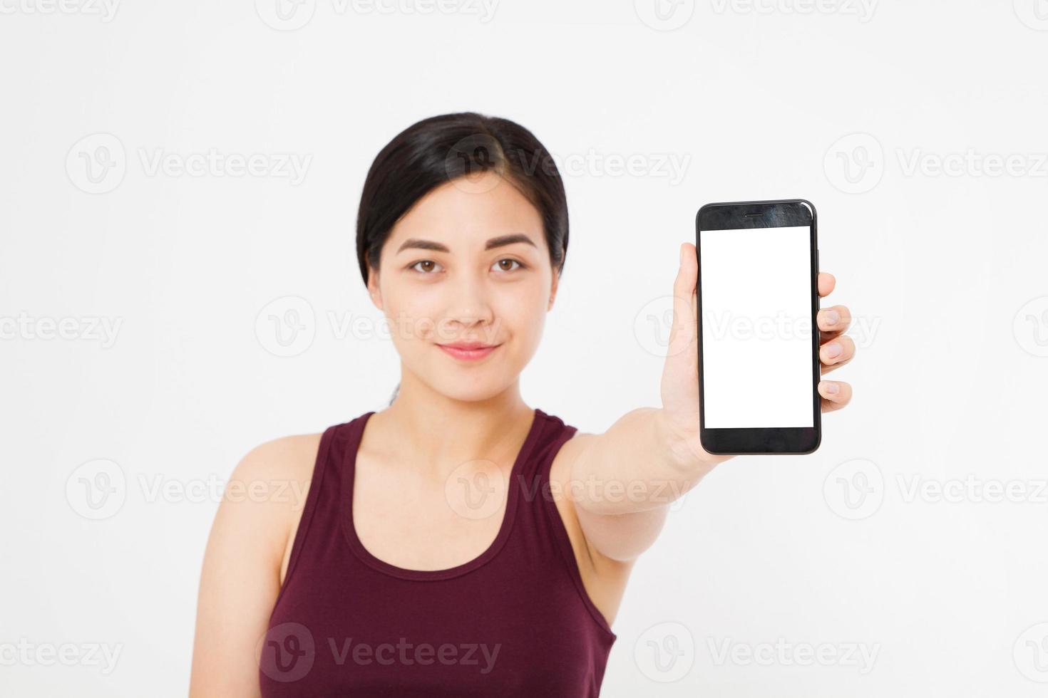 Smiling asian, japanese woman hold black smartphone, cellphone isolated on white background. Selective focus. Copy space. photo