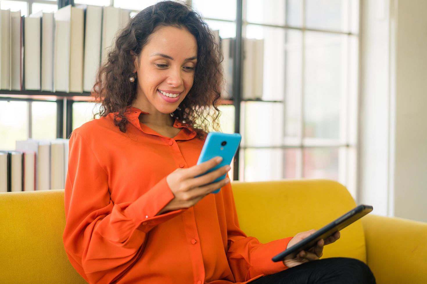 Latin woman using mobile phone or smartphone and holding tablet photo
