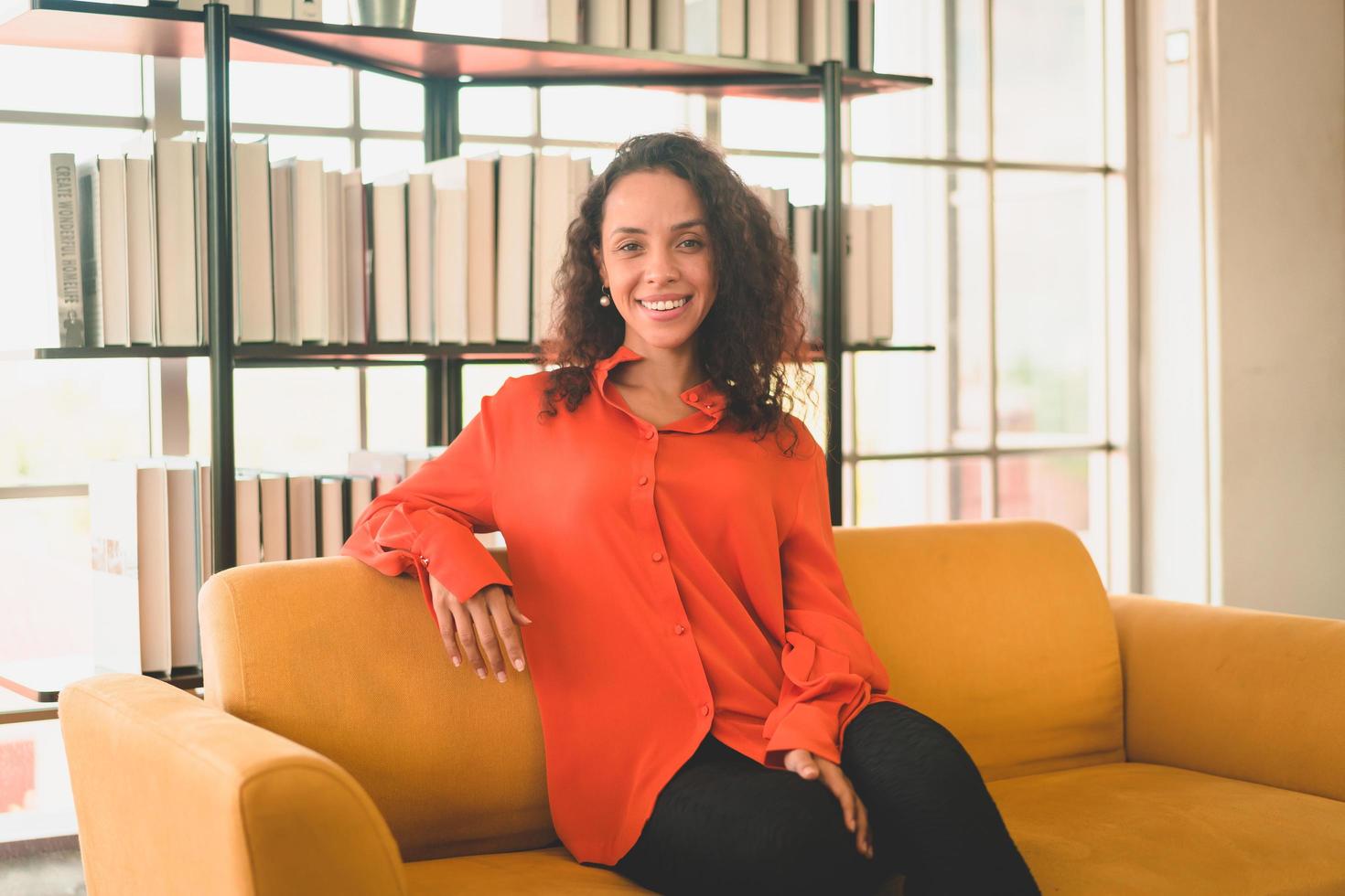 happy latin woman sitting on a comfortable sofa photo