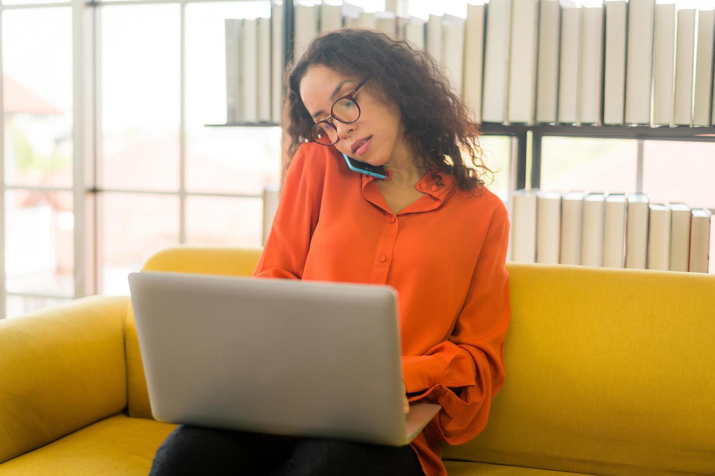 latin woman working with laptop on sofa photo