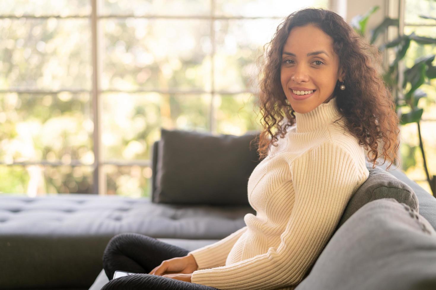 Latin woman smiling and sitting on sofa photo