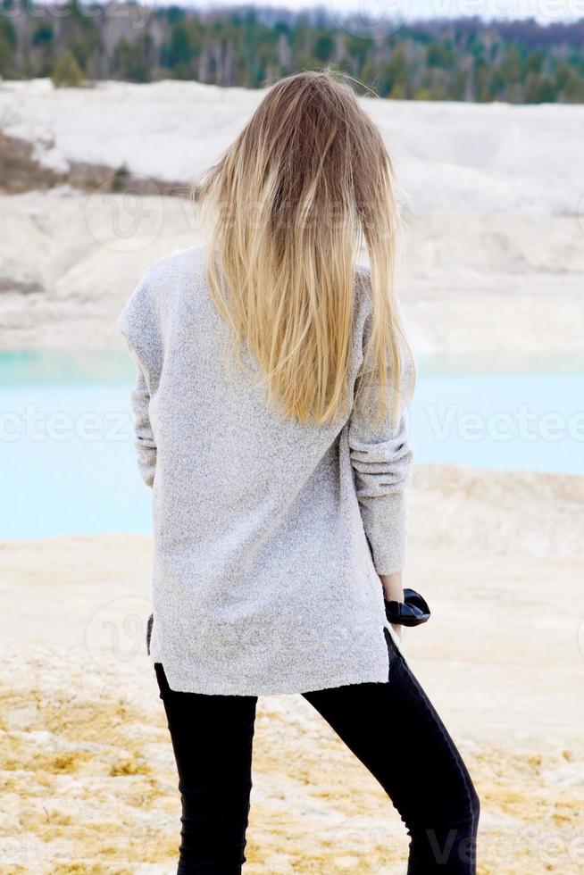 Beautiful teen woman posing at blue lake and yellow sand photo