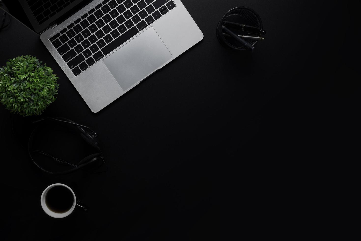 Vista superior de la mesa oscura y negra con ordenador portátil y suministros de oficina de negocios trabajando foto