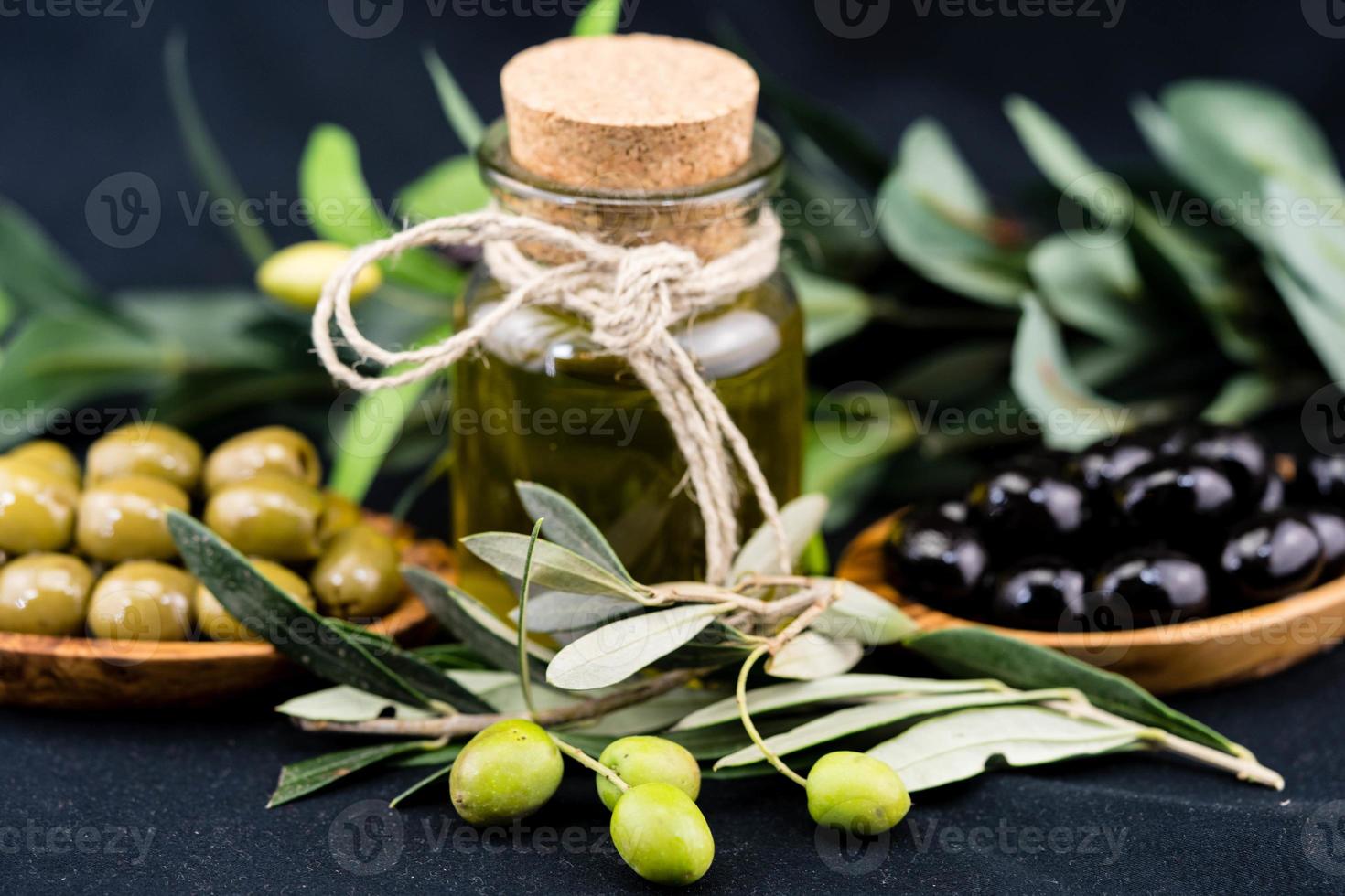 cold pressed olive oil with branch and fruits photo