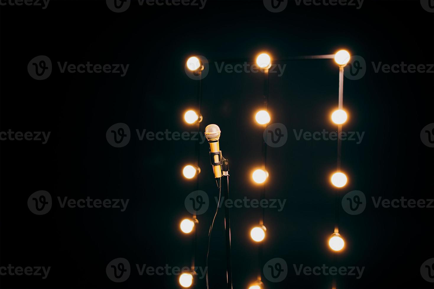 gold microphone on microphone stand on dark background with many lights photo