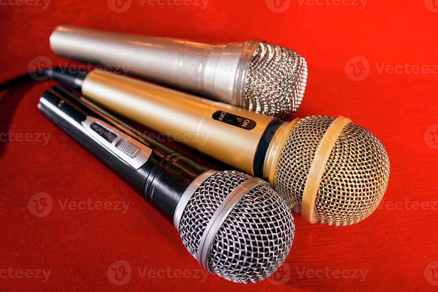 gold, silver and bronze microphones on red wooden background photo