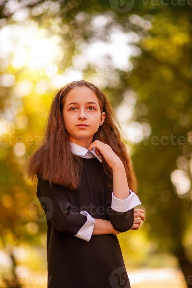 concepto de escuela. niña de 11 años con un vestido en el fondo de la naturaleza en otoño. foto