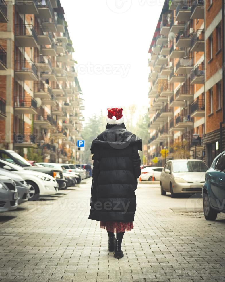 Woman walks in the street during quarantine with cars and houses in the background. Quarantine in Georgia.Saburtalo. Urban city lifestyle in winter 2020. photo