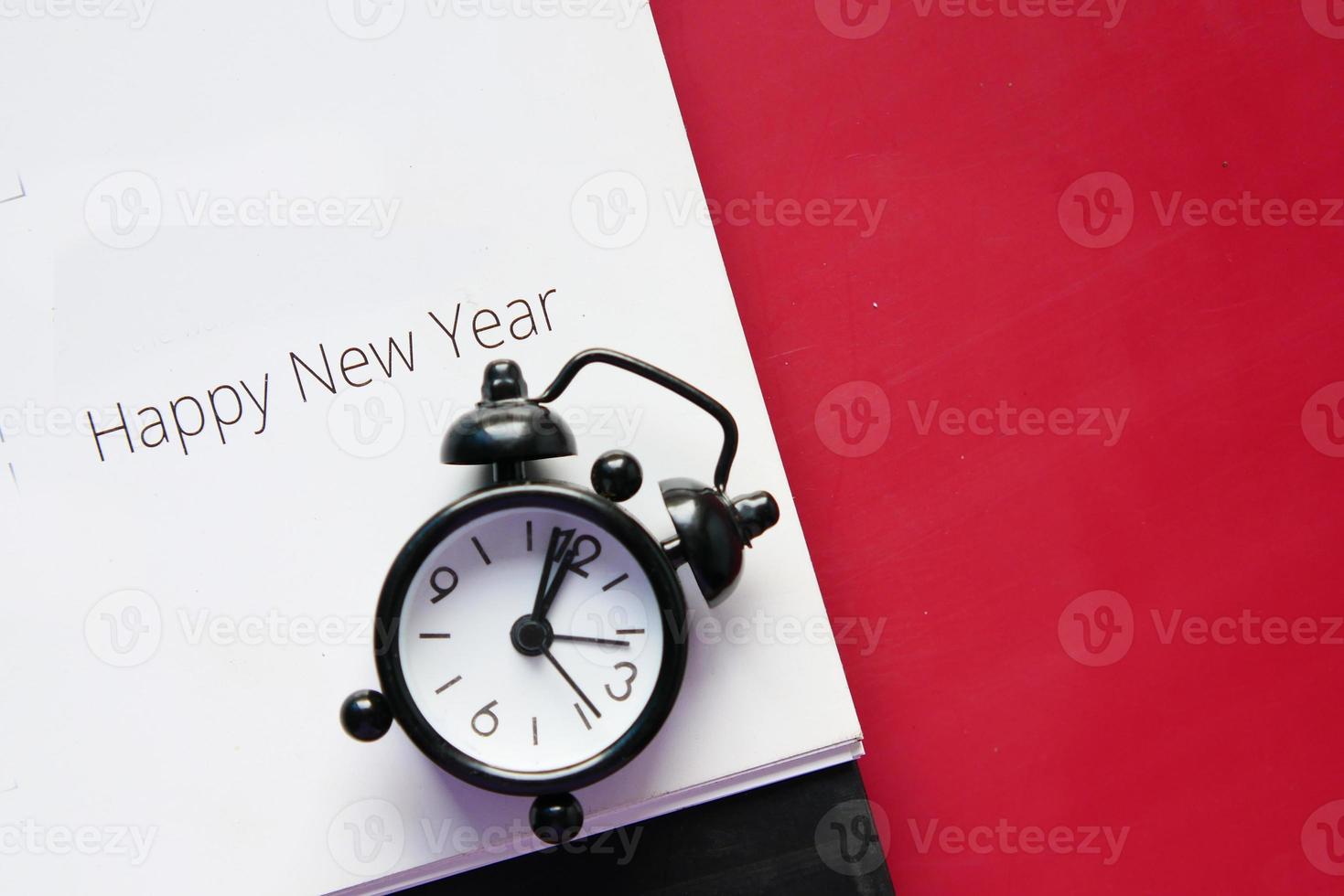 Feliz año nuevo texto en calendario con reloj en mesa foto