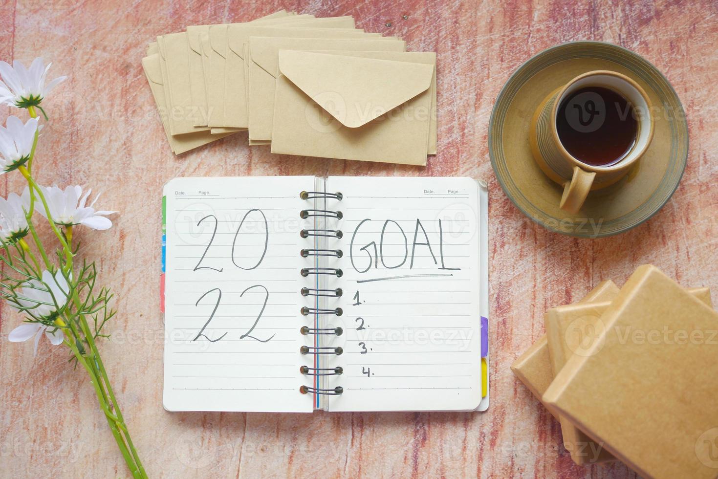 2022 new year goals on notepad with tea and box on table photo