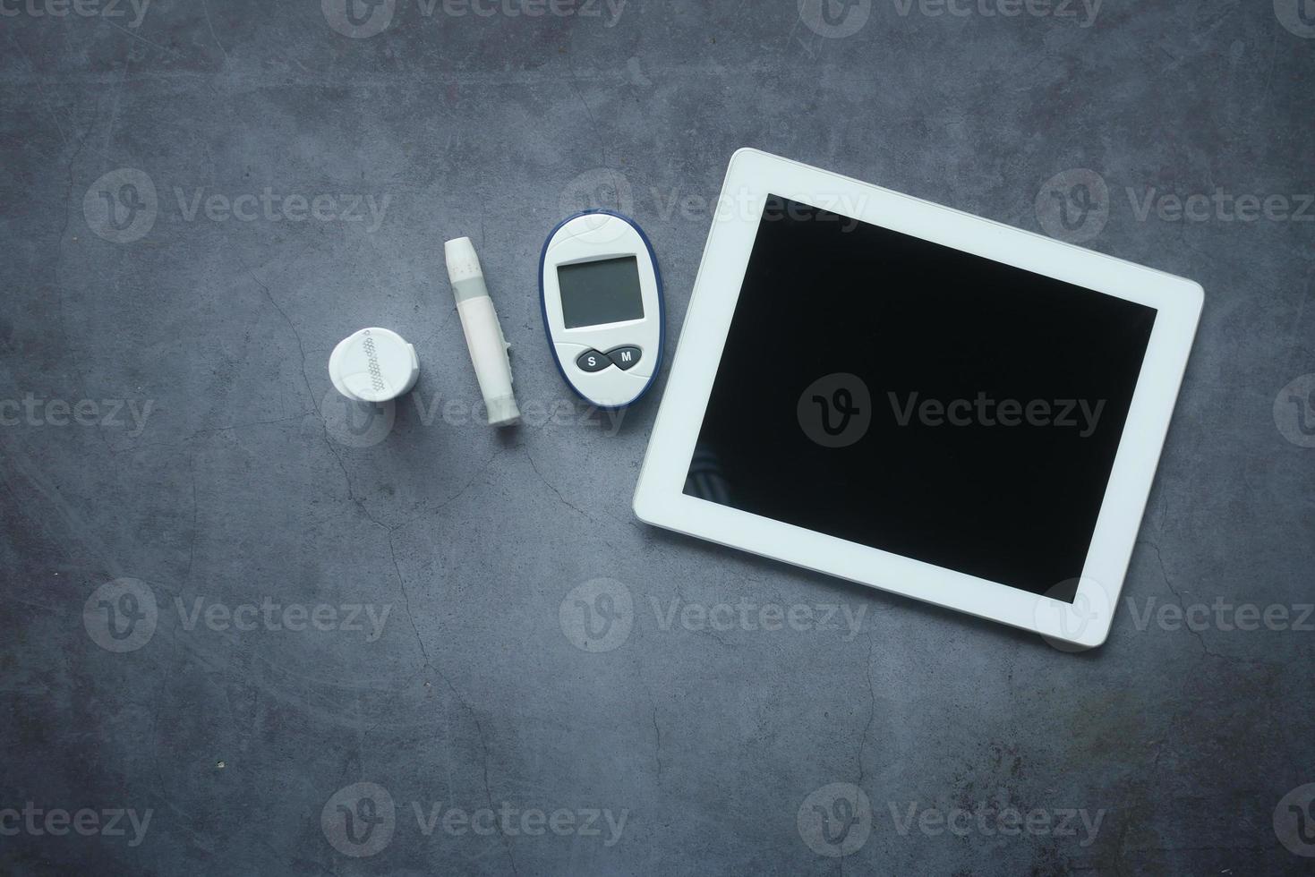 top view of digital tablet and diabetic measurement tool on table photo